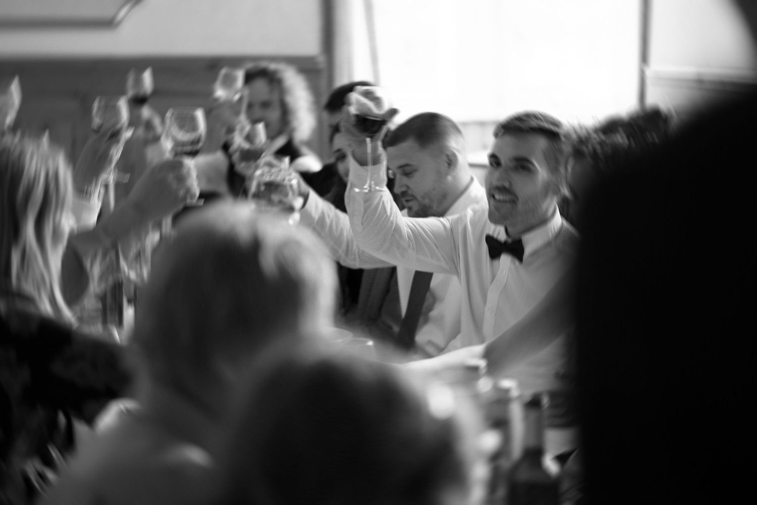 Black and white candid shot of wedding reception guests during dinner service.