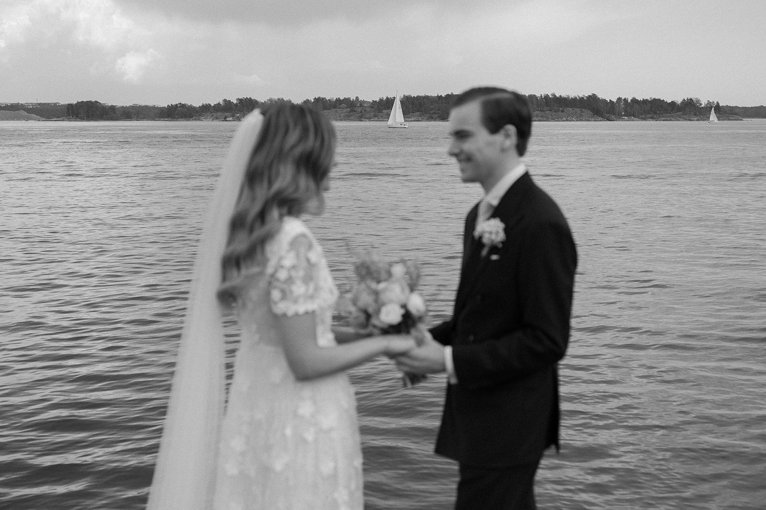 Romantic black and white wedding portraits by the water showing intimate moments between newlyweds.