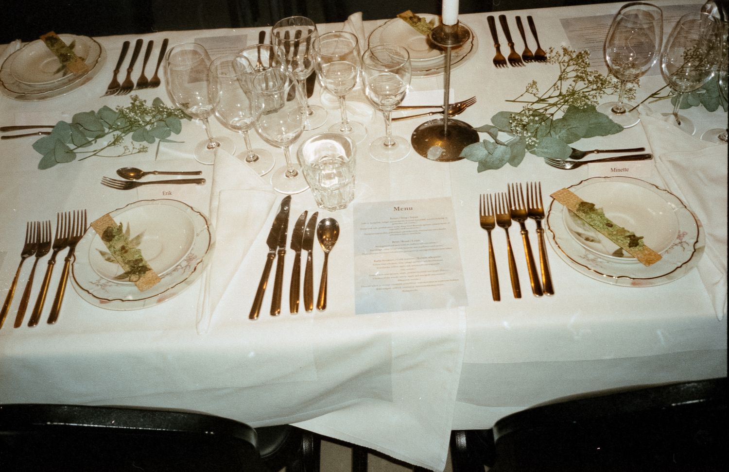 Elegant formal dining table setting with white linens, crystal glasses, and polished silverware arranged for a special occasion.