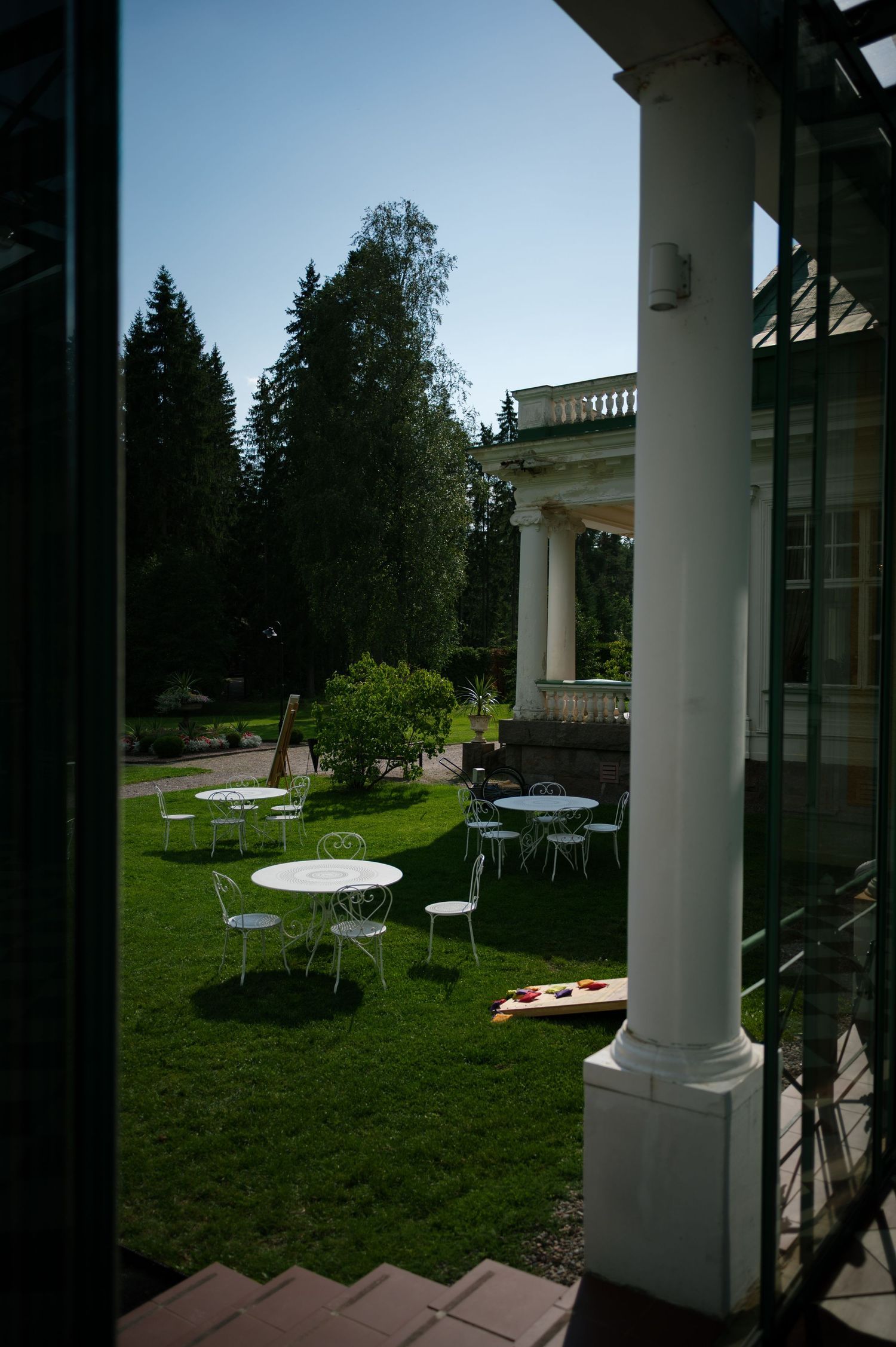 White columned veranda overlooking a manicured lawn with outdoor seating areas.
