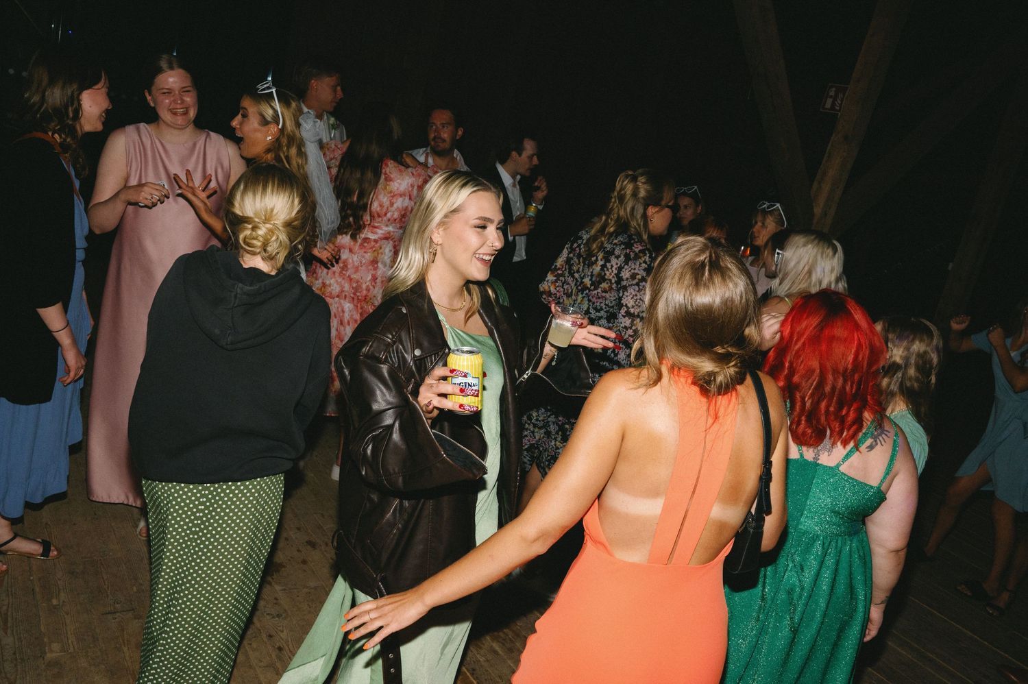 Wedding party dancing together in a dark venue with decorative lighting.