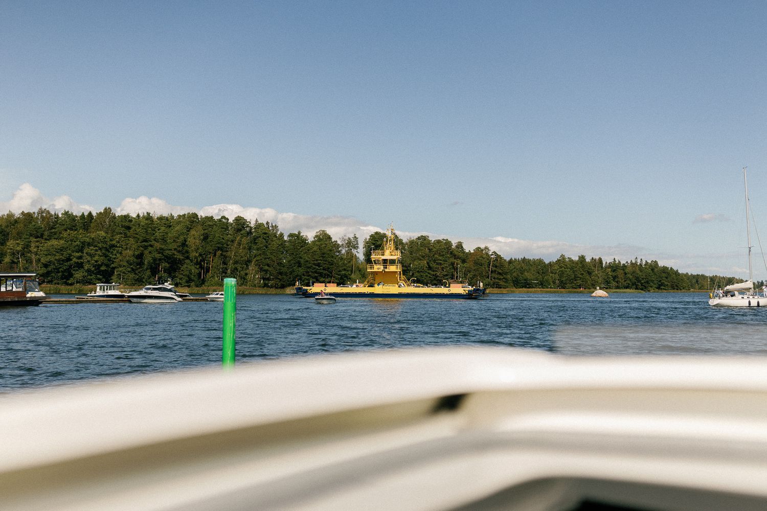 Scenic lake view with boats and tree-lined shore under blue skies.