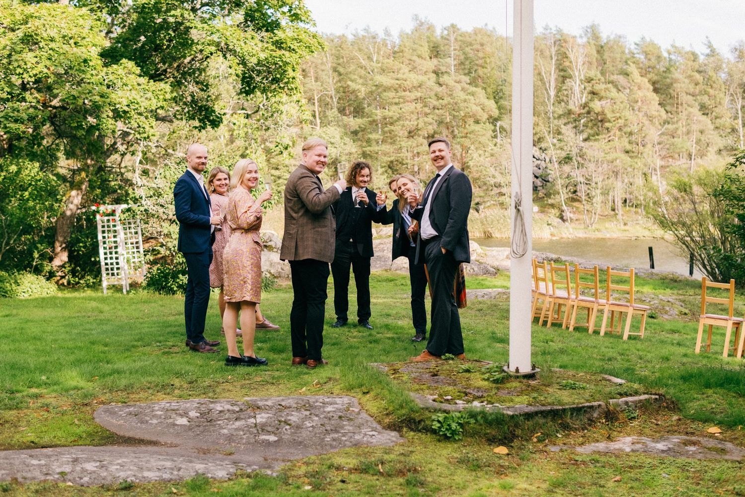 Outdoor gathering of guests on a lush green lawn near trees.