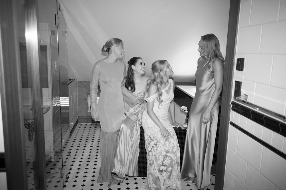 Black and white photo of people gathered in a tiled bathroom space.