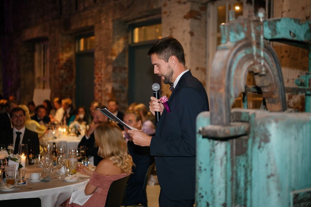 Industrial-style wedding venue with exposed brick walls and elegant table settings illuminated by ambient lighting.