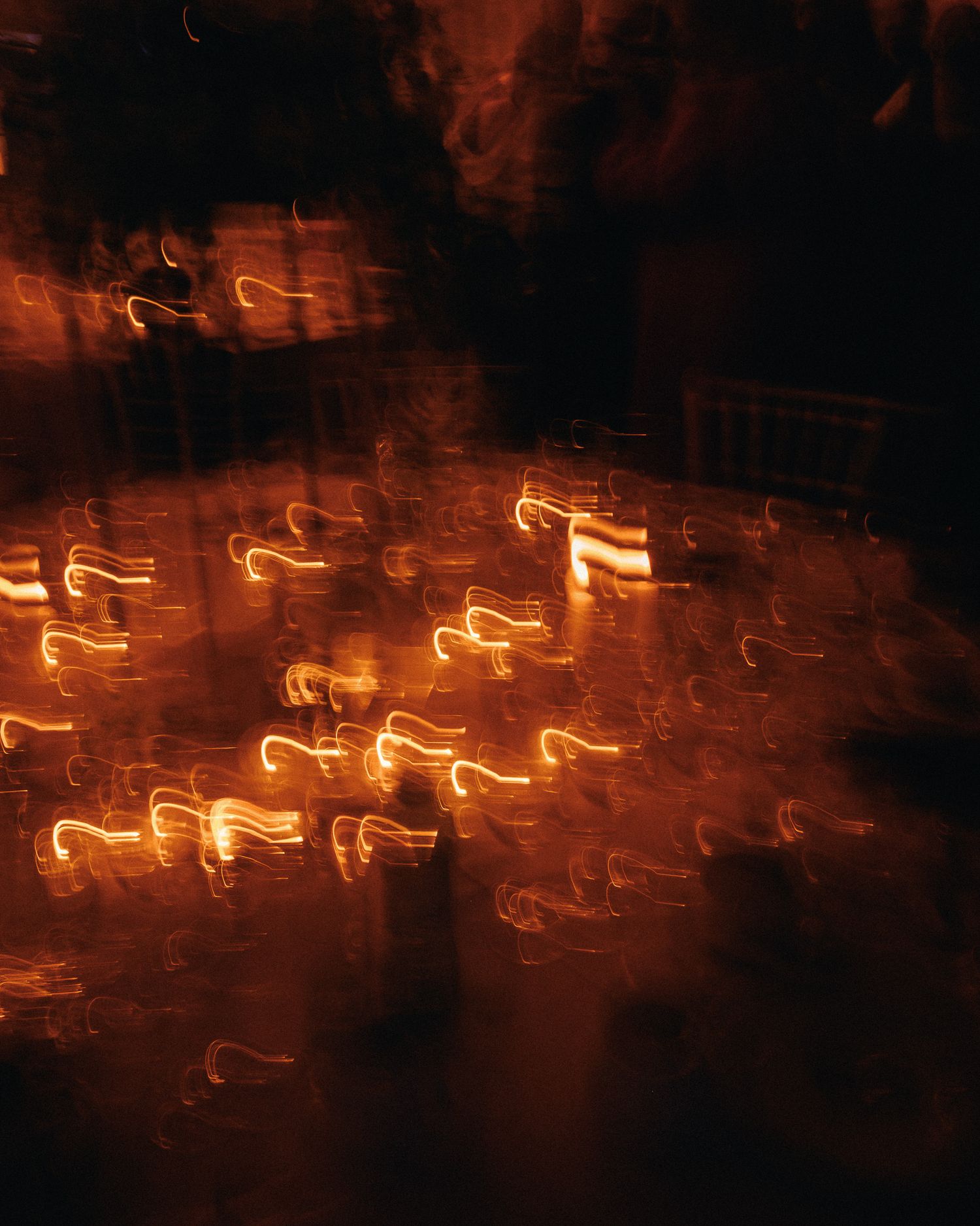 Abstract long exposure photography of glowing orange light trails against a dark background.