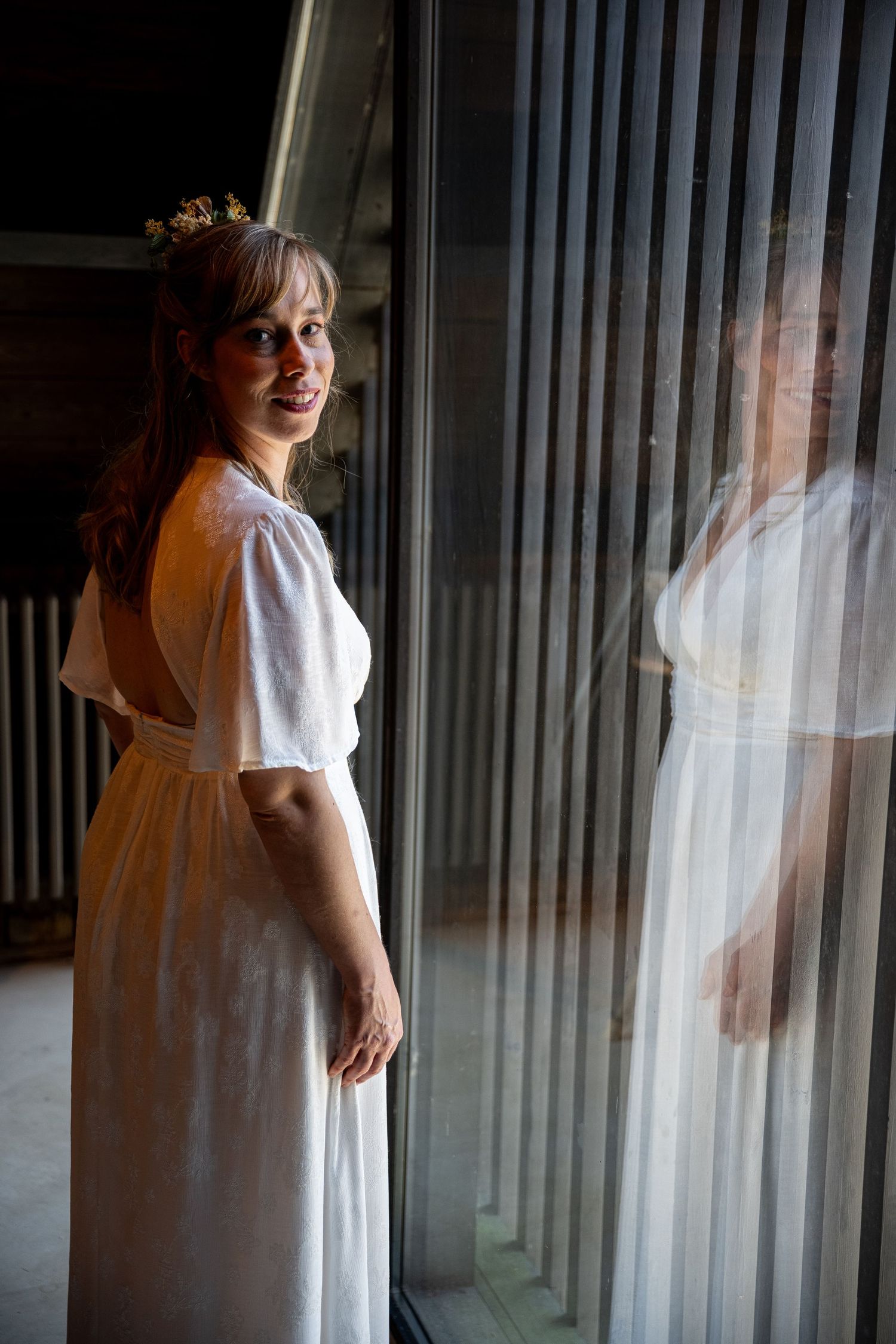 Artistieke huwelijksfoto met weerspiegeling van de bruid in een venster in Doornik