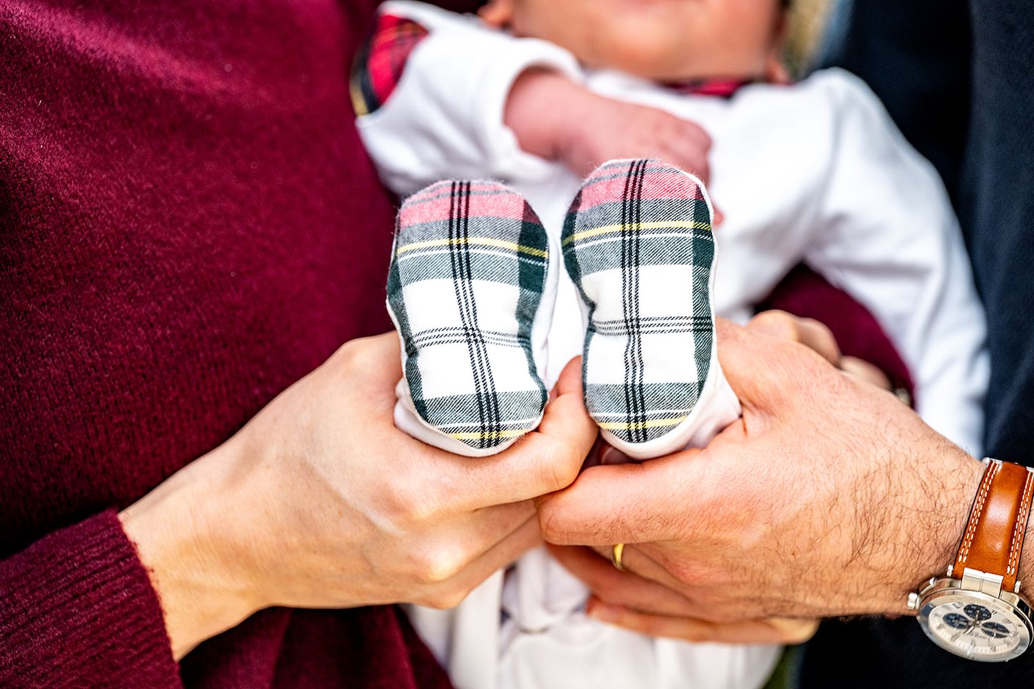 Newborn shoot in Koolskamp met kerstkledij, ouders houden de voetjes van hun kersverse kindje vast