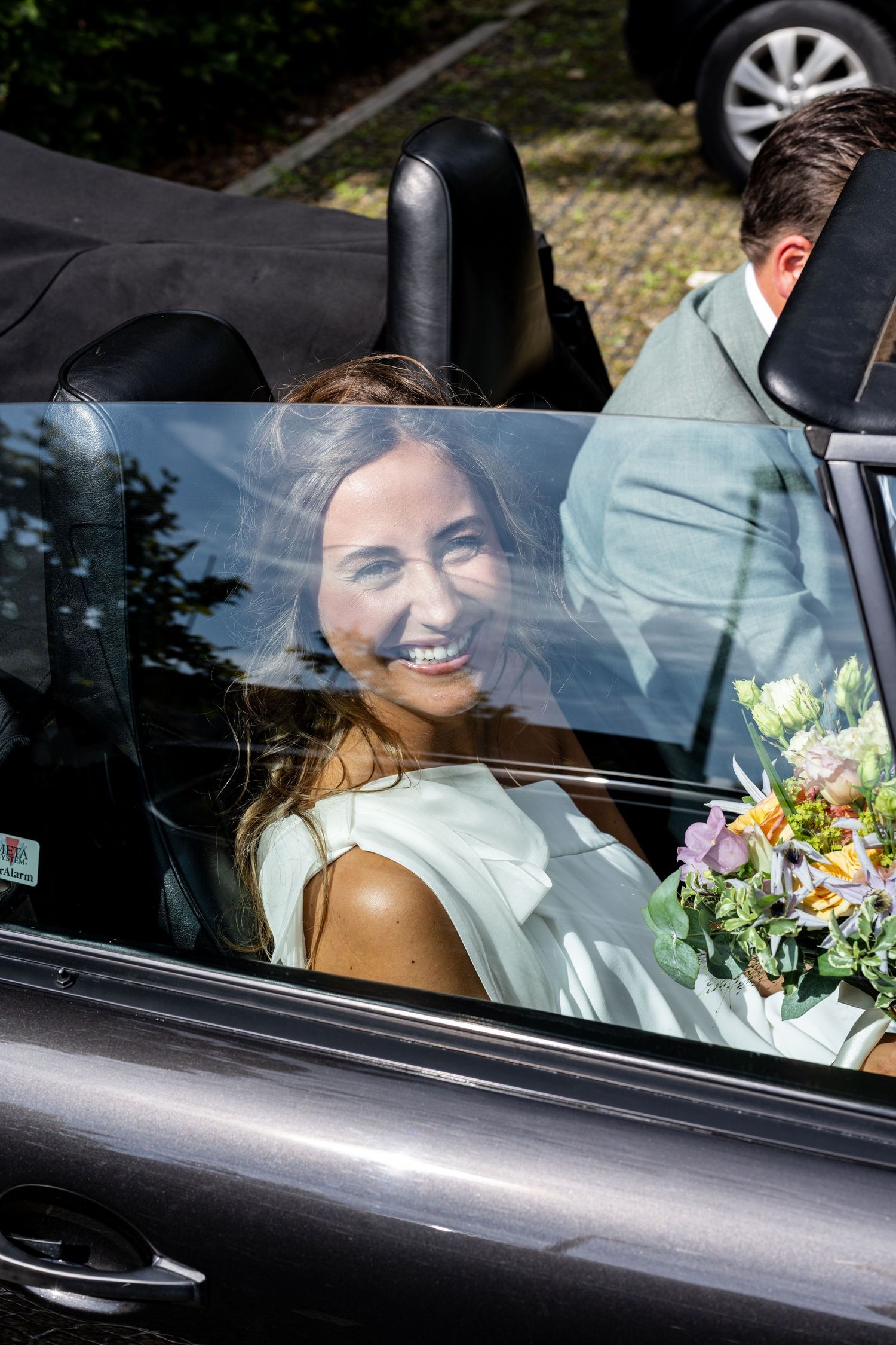 Bruid gefotografeerd door de ruit van de oldtimer