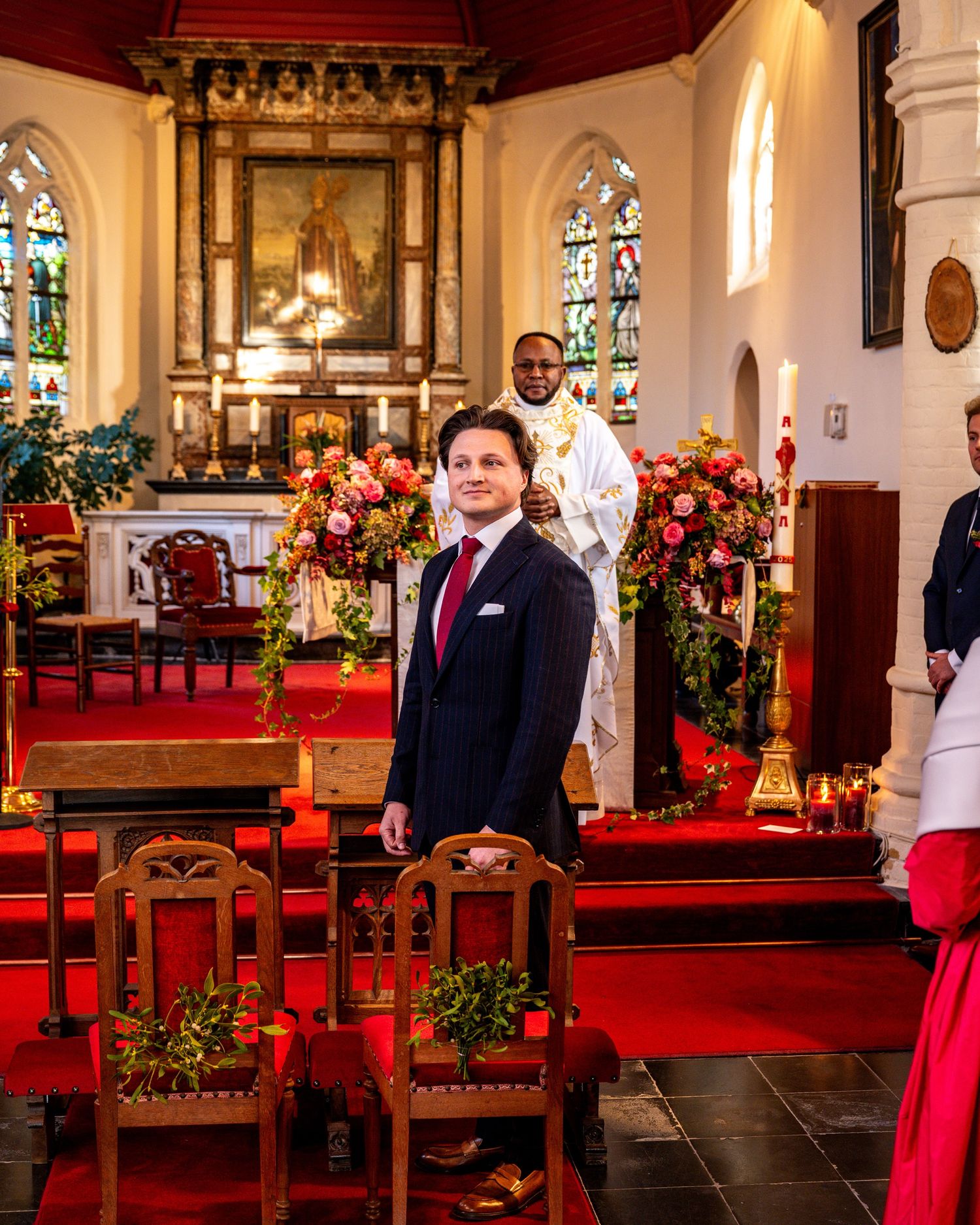 Huwelijksfoto's in kerk, bruidegom wacht tot bruid met vader binnenkomt