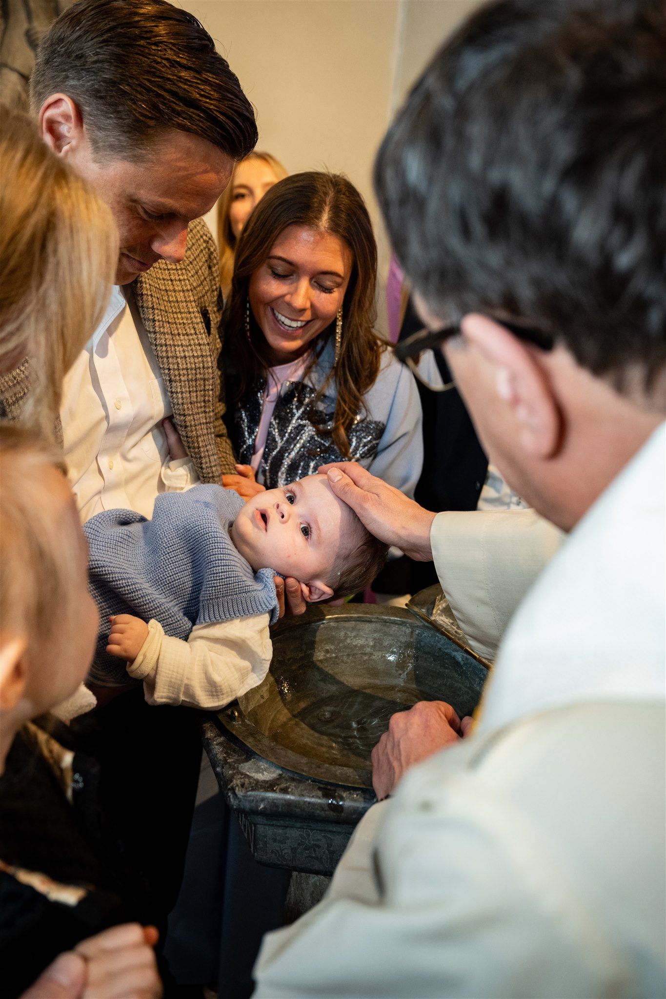Baby wordt gedoopt aan de doopfont in kerk in Afsnee, regio Gent