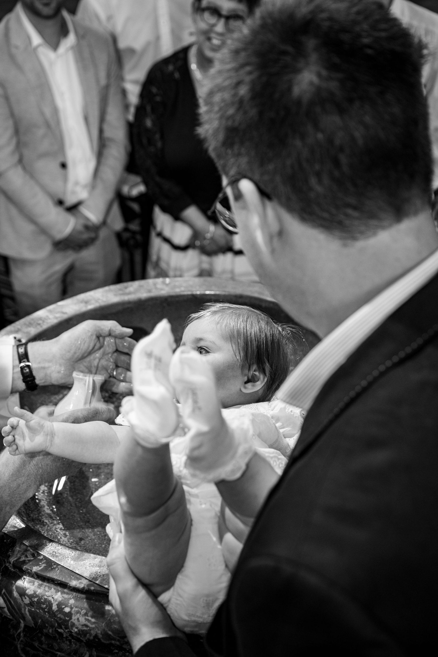 Baby wordt gedoopt aan de doopfont in kerk in Ledegem