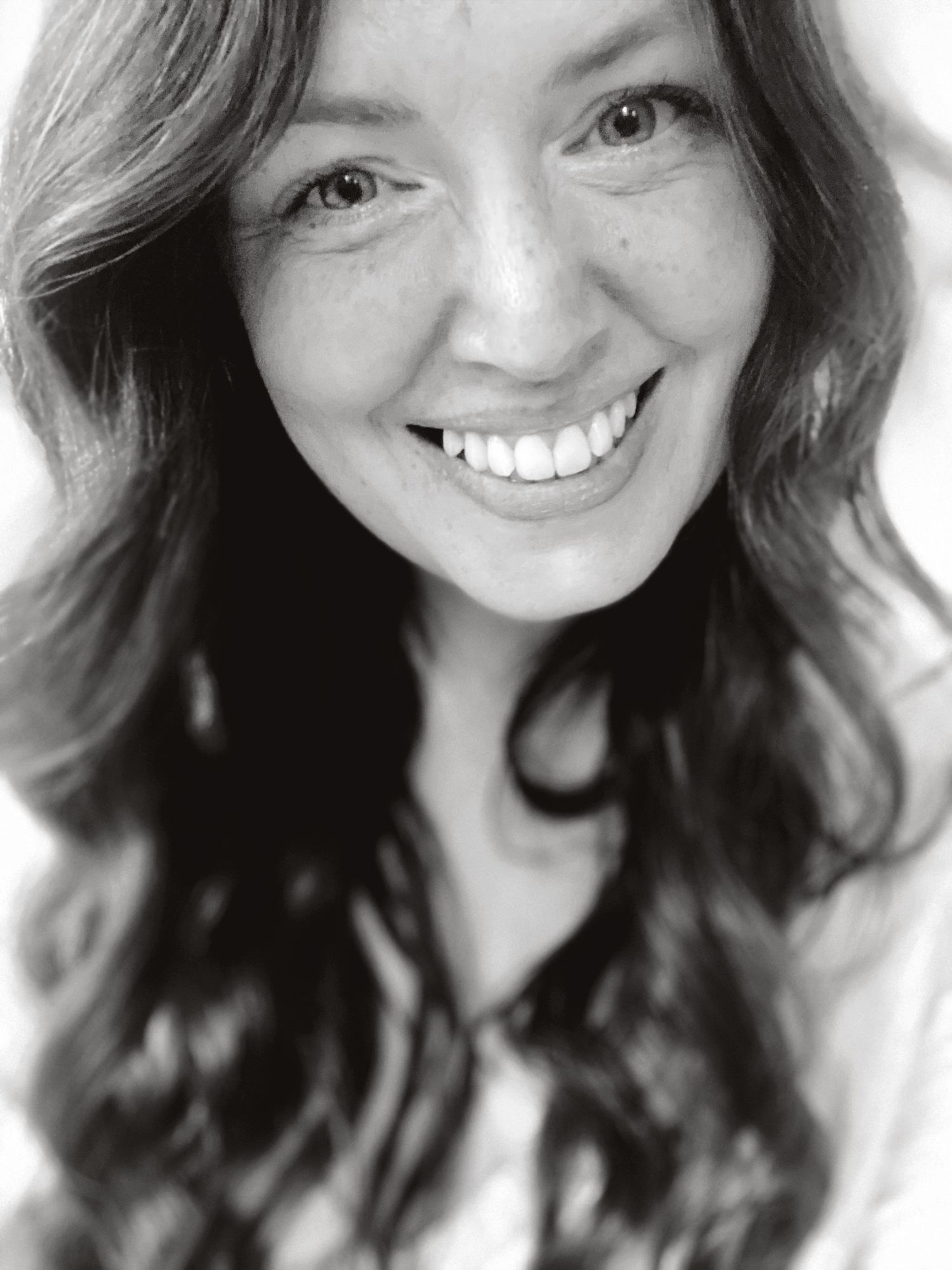 Black and white photo of a smiling photographer who offers family photography in Portland, Dorset