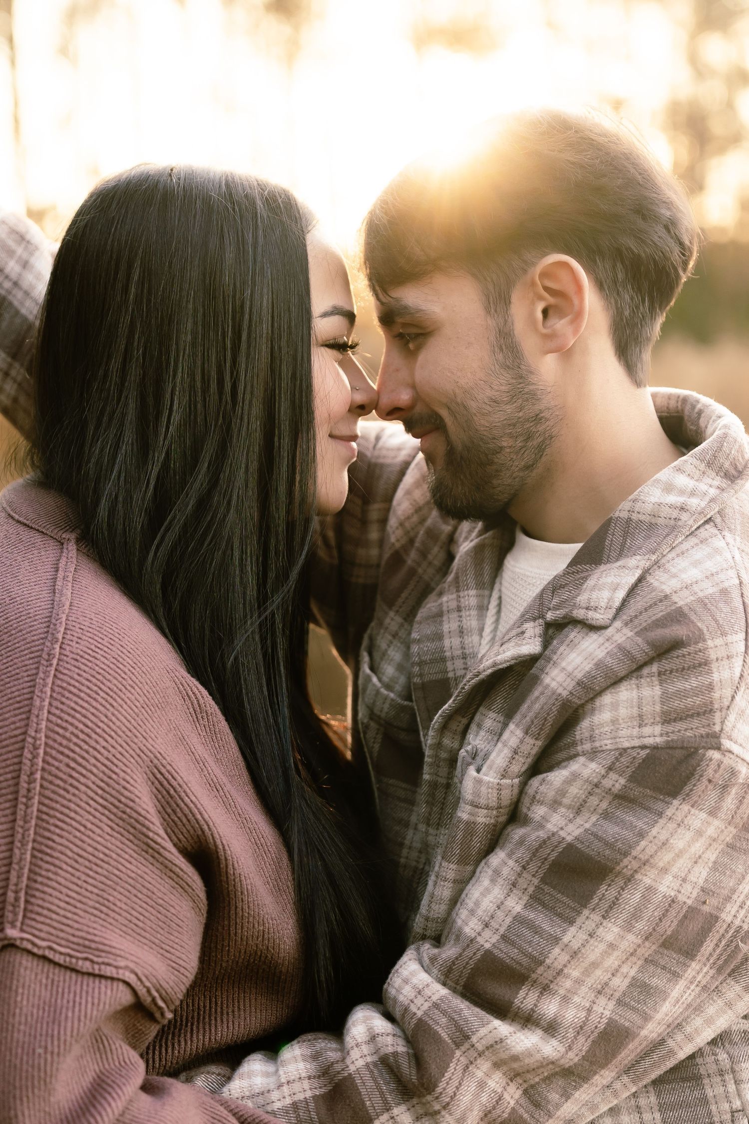 Romantic couple in casual attire sharing intimate moments in warm lighting.