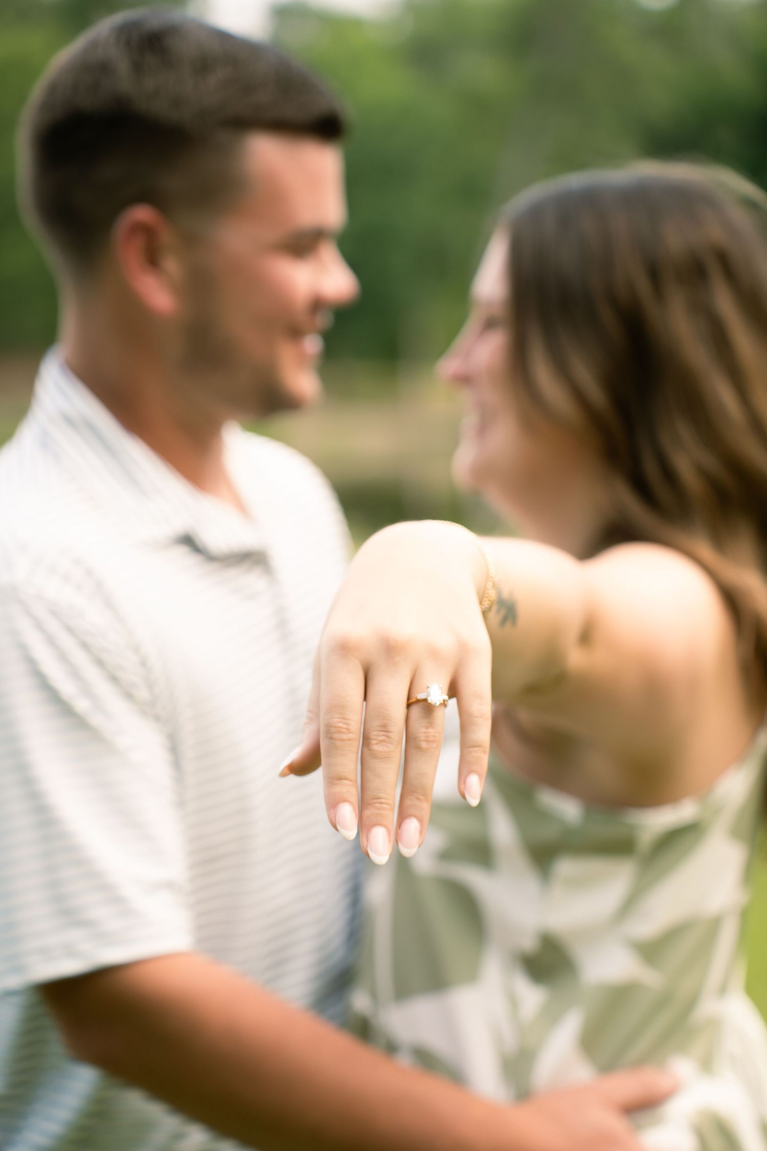 Close-up shots of an engagement ring on hand with couple in soft focus background.
