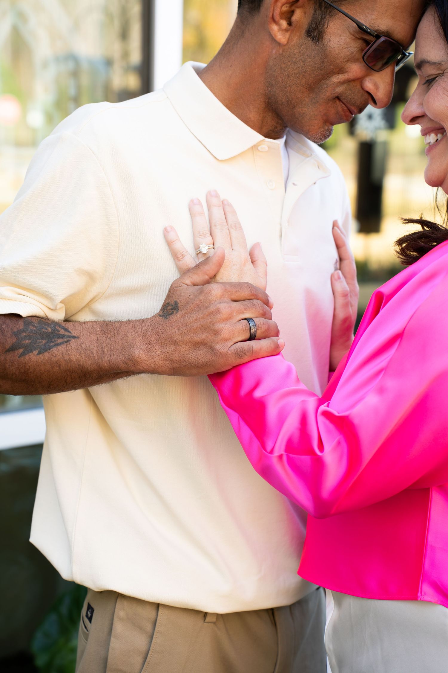 A couple sharing a tender moment, the woman in pink jacket touching the man's chest while he holds her hand gently.