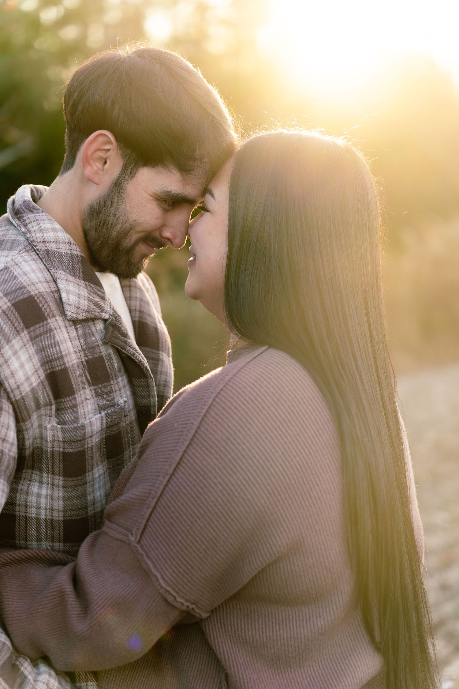 Romantic couple sharing an intimate moment outdoors, bathed in warm golden sunset light.