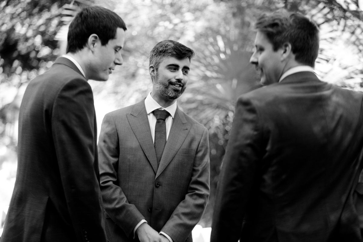 Group of men in formal suits engaged in conversation at an outdoor event.