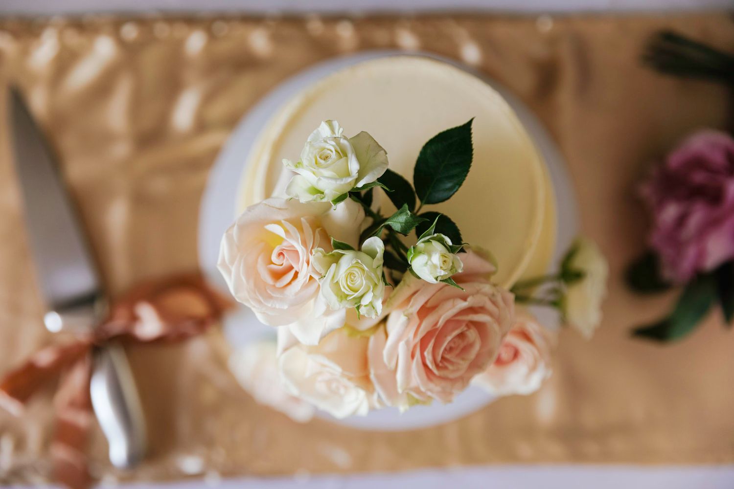Delicate peach and cream roses arranged in elegant wedding table centerpieces with soft candlelight.
