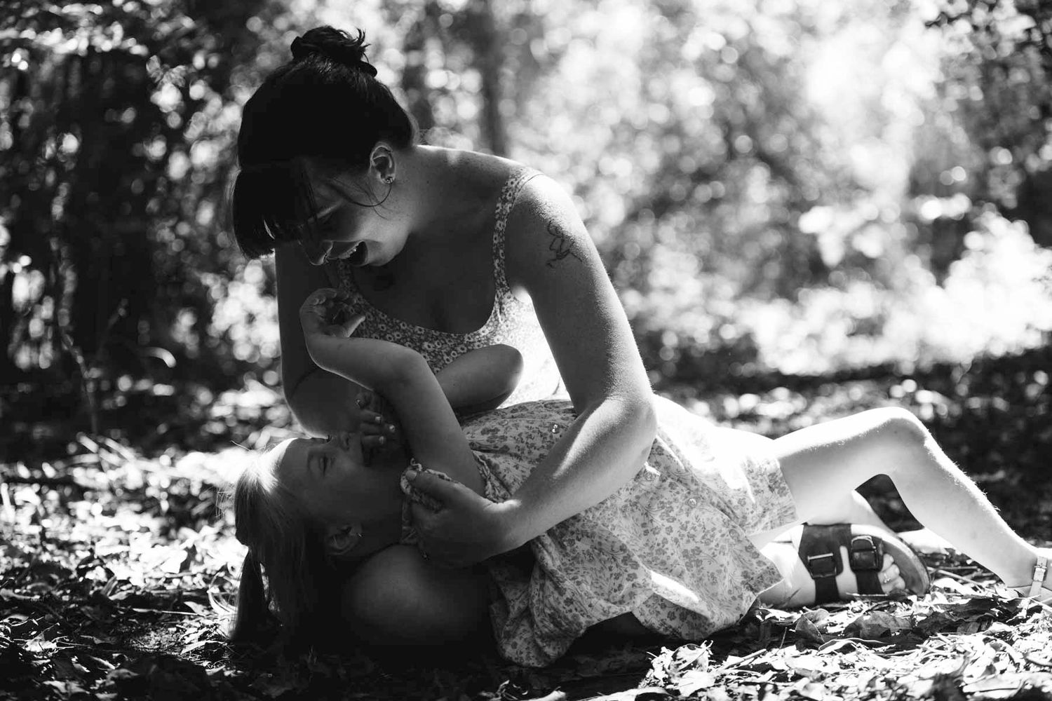 A romantic couple lying in grass shares an intimate moment together in black and white photography.