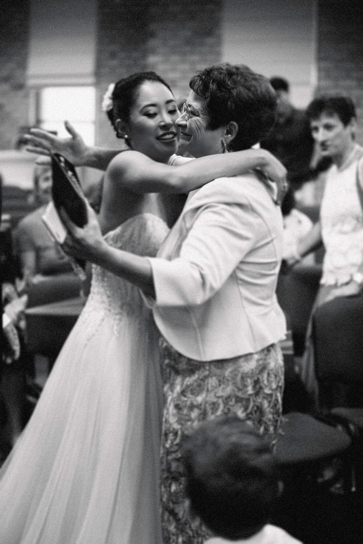 People dancing together in elegant white attire at a wedding reception.