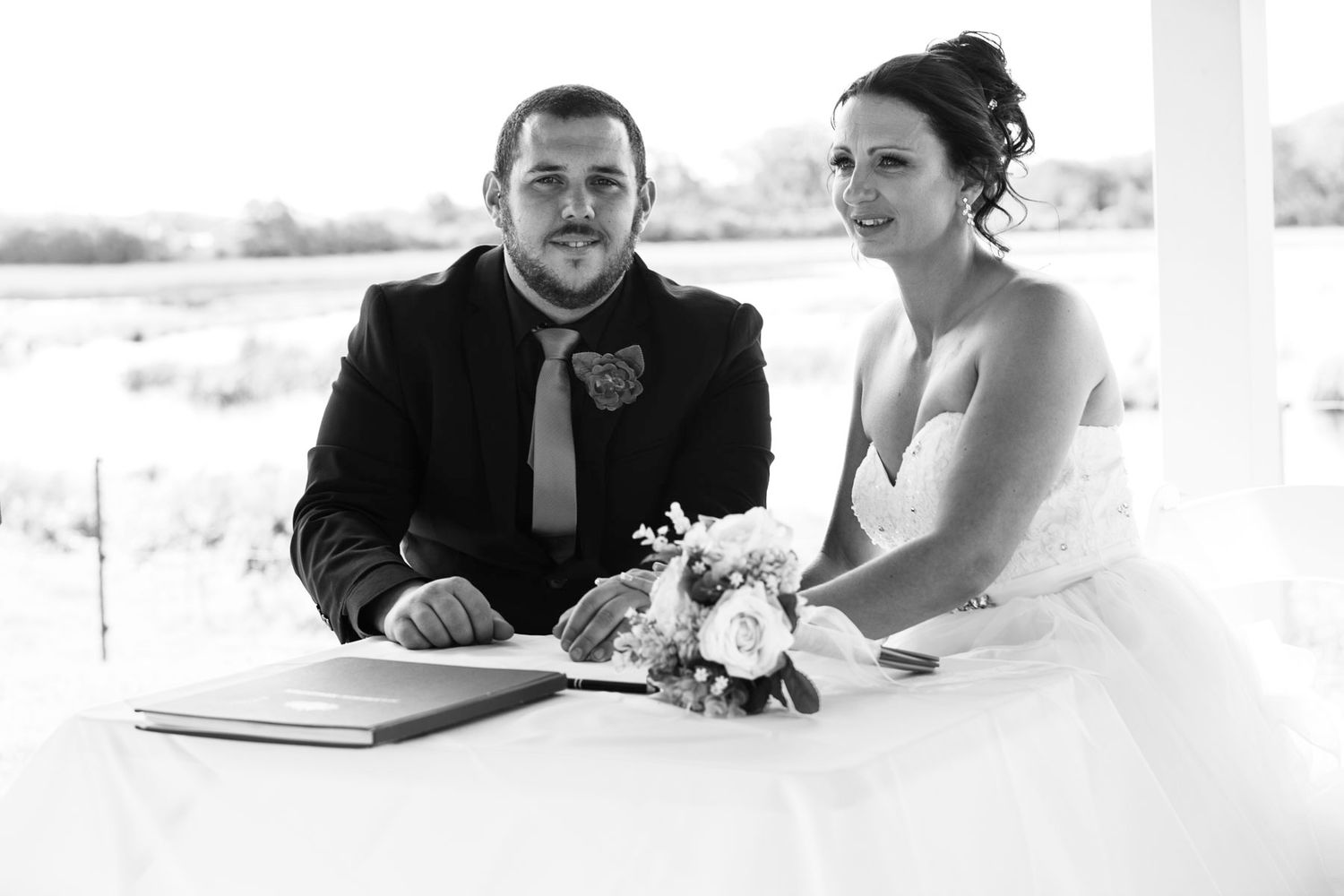 Black and white wedding reception photo showing guests seated at a table.