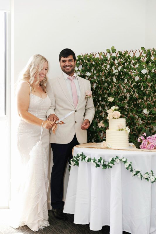 A couple cuts their wedding cake together at an elegantly decorated reception table.