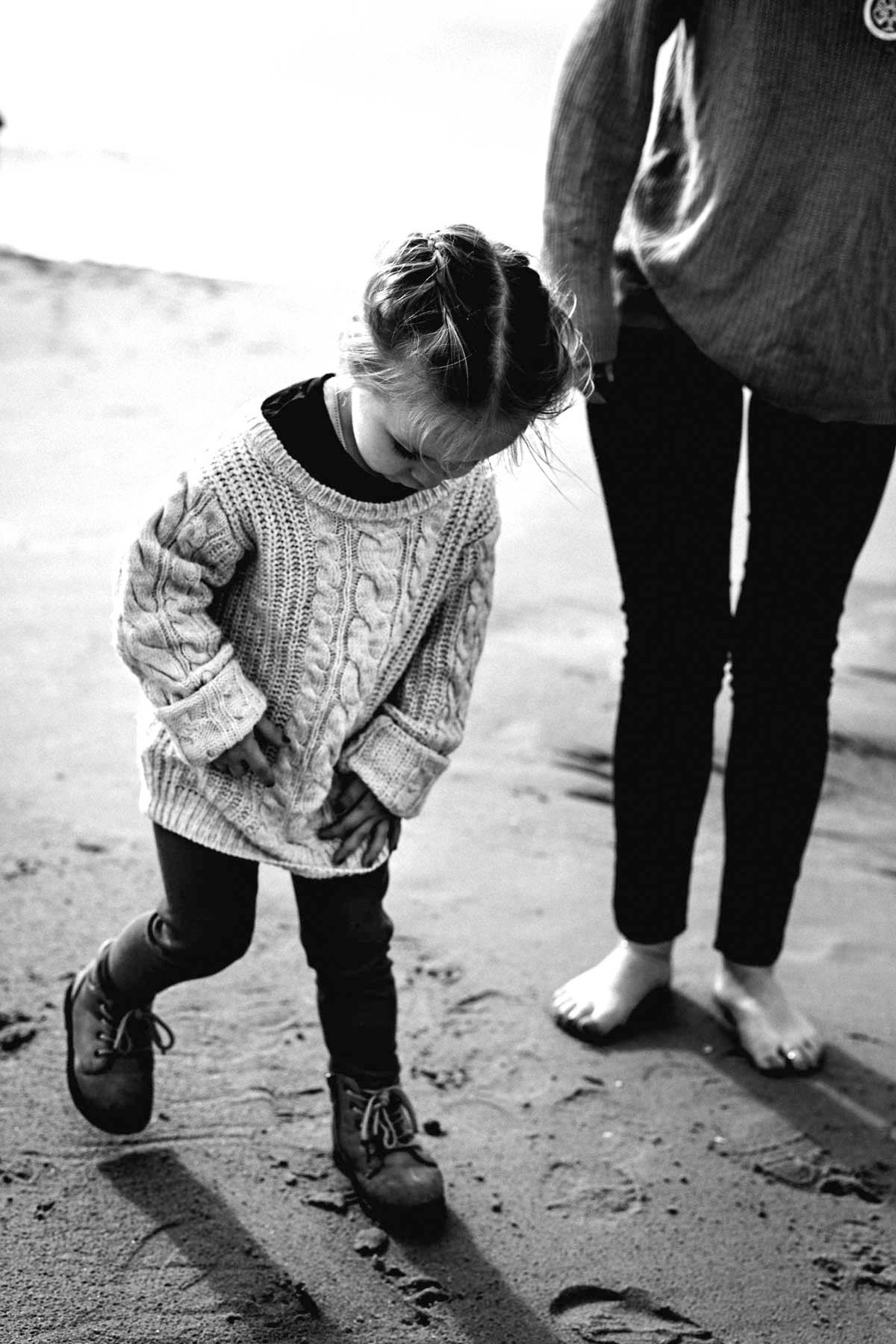 A series of black and white photos showing feet in knit sweaters and dark pants walking on a textured surface.