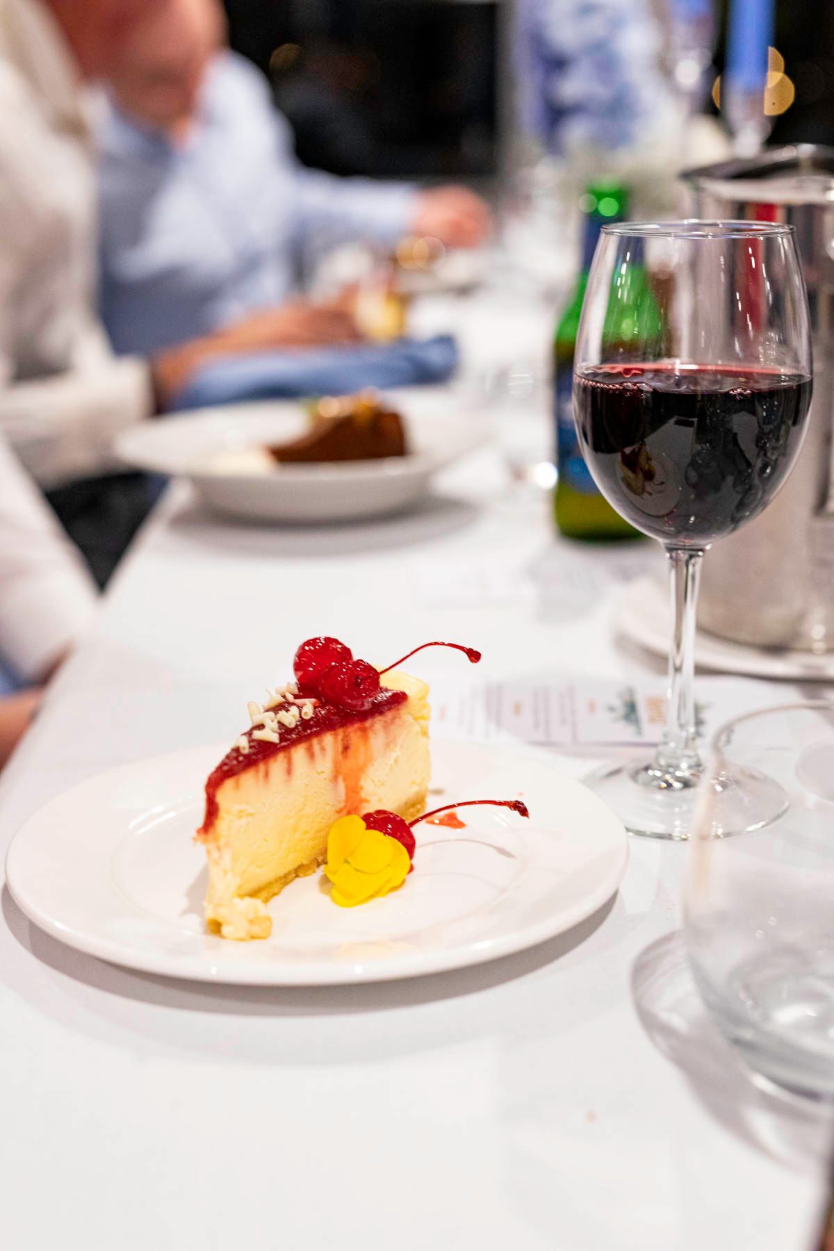 A series of elegant plated desserts with fresh berries and garnishes served alongside red wine glasses at an upscale restaurant.