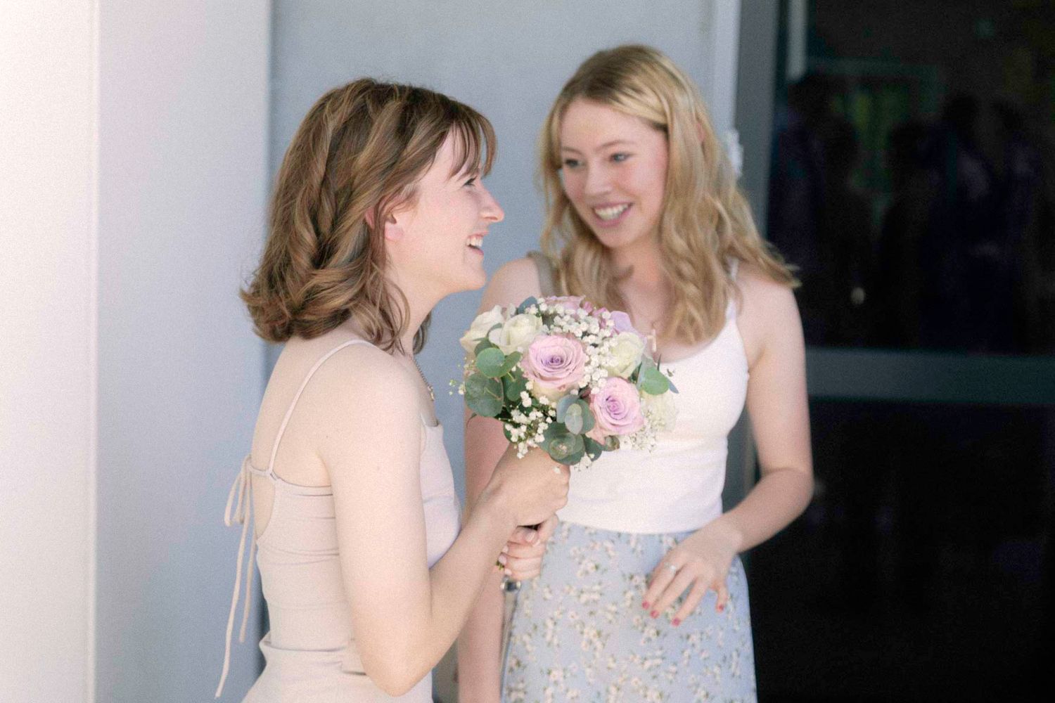 Two people share a joyful moment in formal attire while holding drinks at a celebratory event.