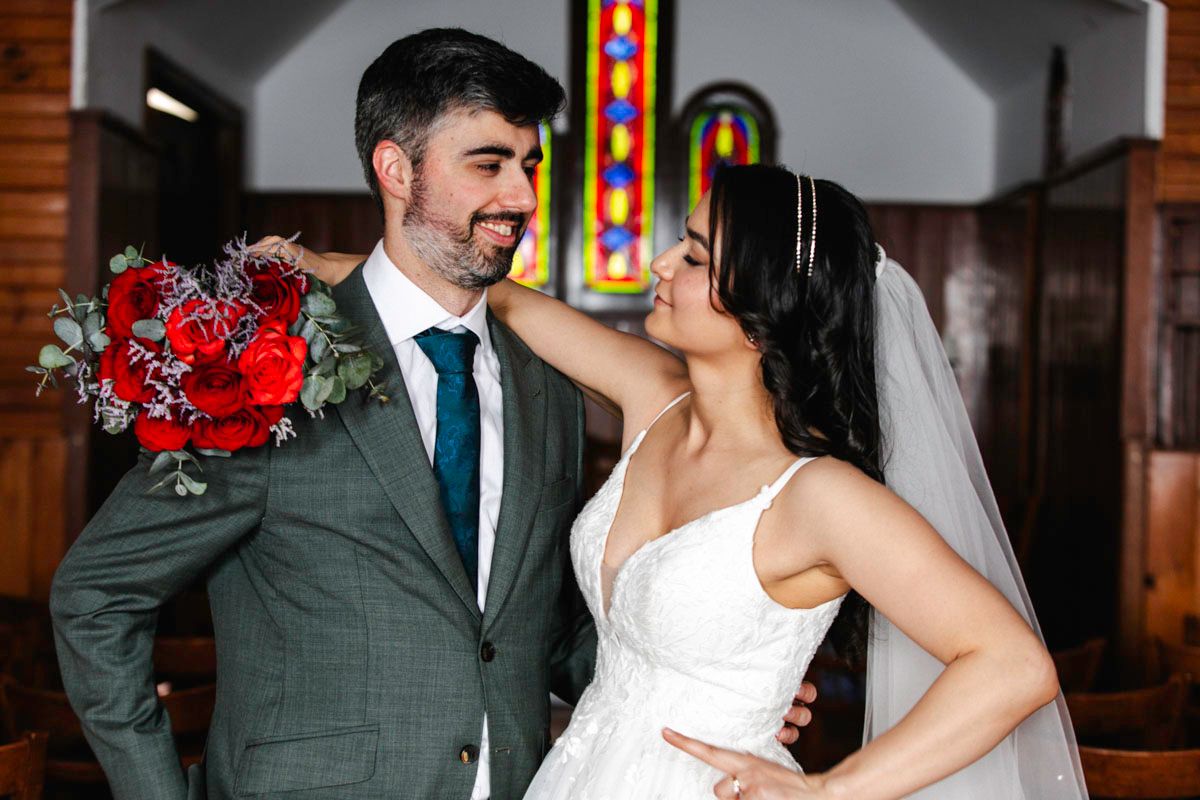 Wedding ceremony moments captured in a church with red floral decorations.
