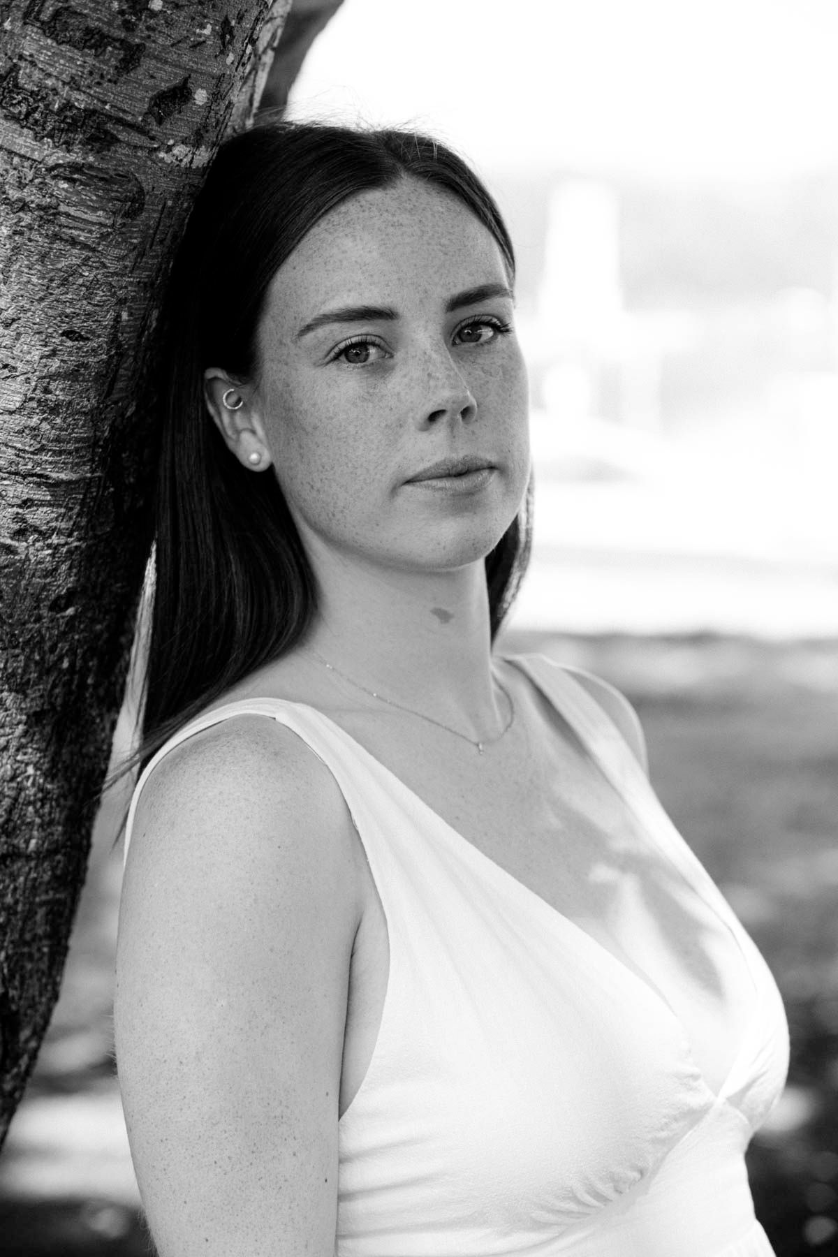 A series of black and white portraits showing a woman in a white top posing against a dark background.