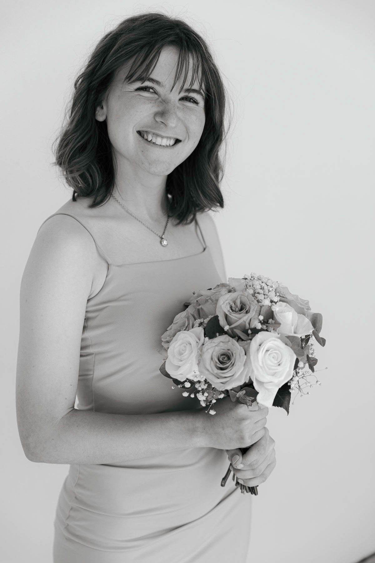 A series of black and white photos showing someone in a sleeveless dress holding a bouquet of roses against a white background.