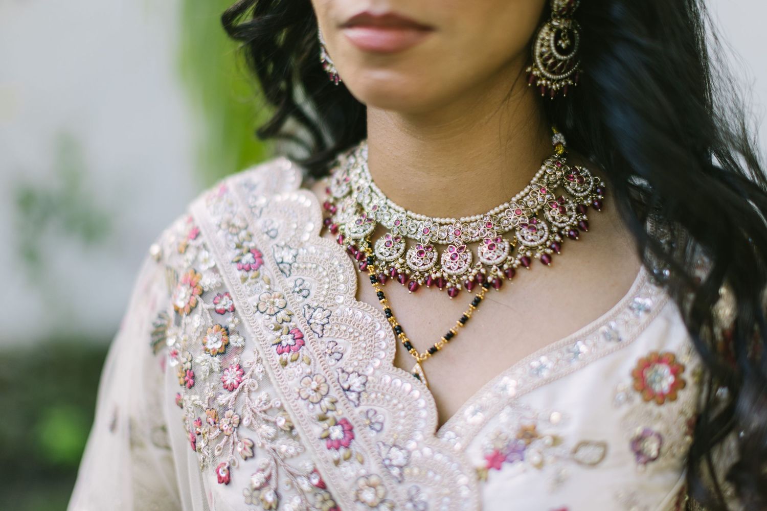 Close-up of an Indian bride wearing an elegant kundan necklace and earrings with intricate embroidered white lehenga.