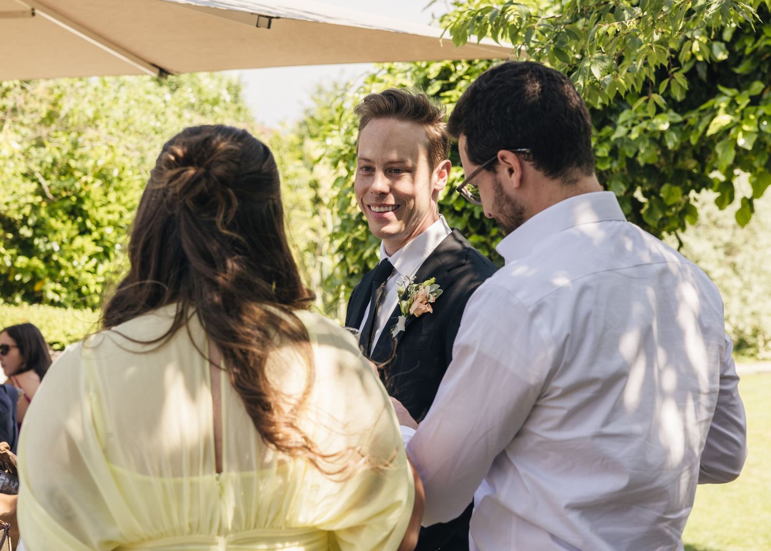 Candid moment of groom smiling with friends and family on his wedding day, captured by EvieSJPhotography.