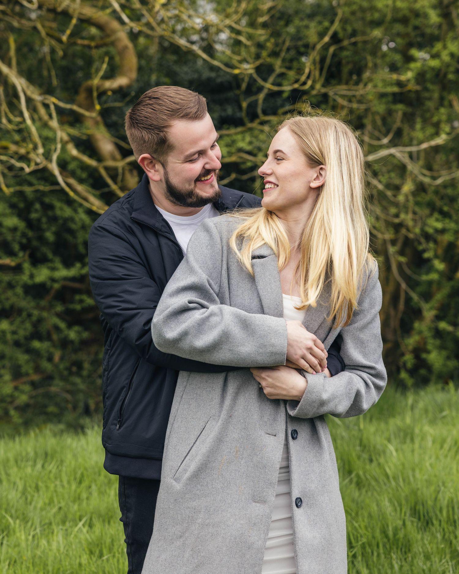 Natural engagement photoshoot of a couple in a field by EvieSJPhotography.