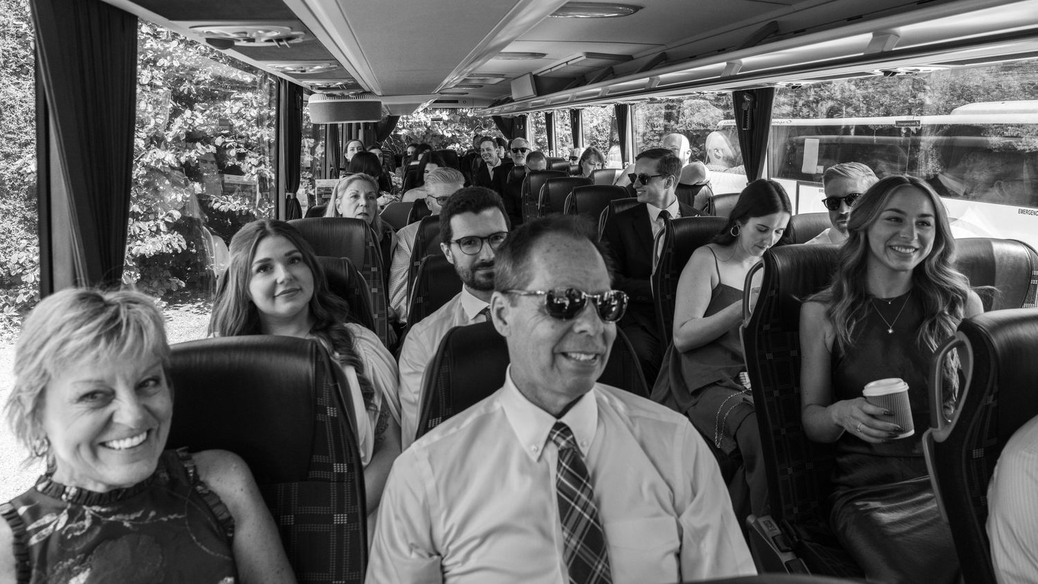 Wedding guests having fun on a bus heading to a different venue, captured by EvieSJPhotography.