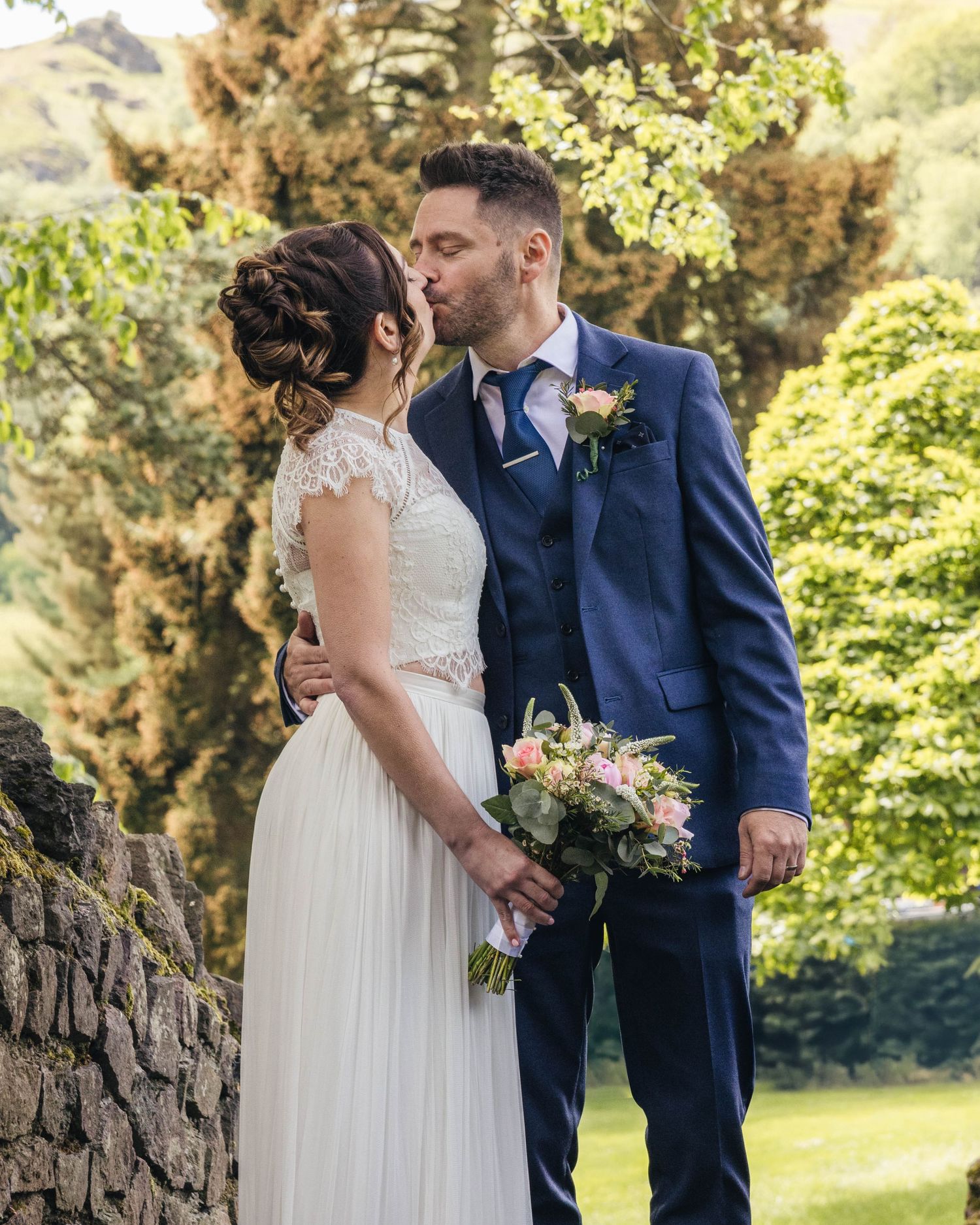 Bride and groom sharing a romantic kiss on their wedding day, captured in a relaxed documentary style by EvieSJPhotography.