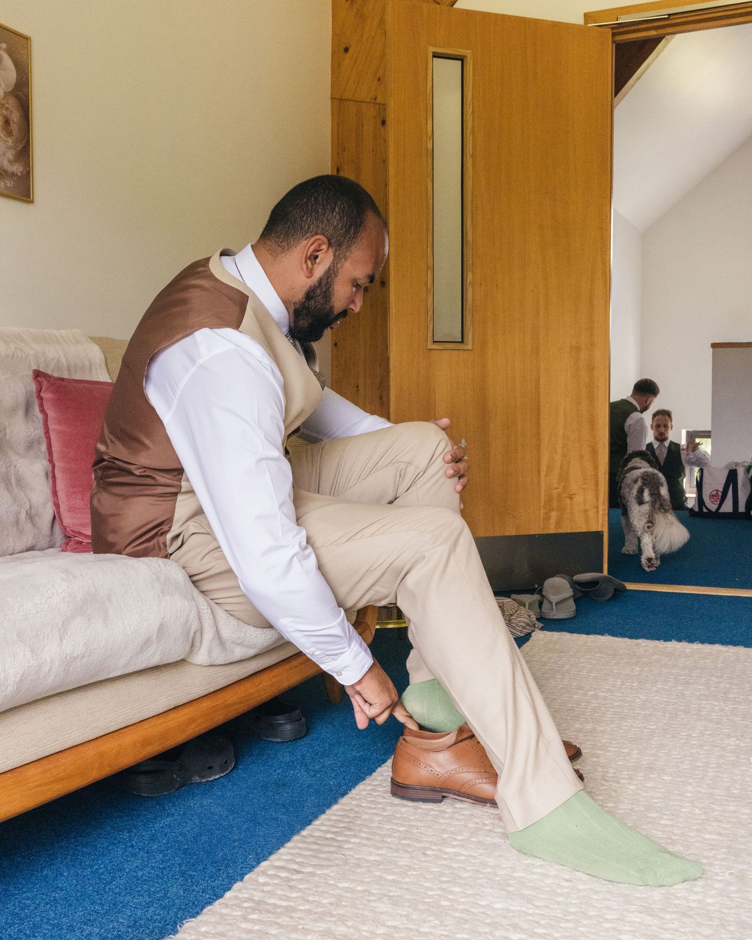 A groom putting his shoes on whilst wearing colourful socks at Rock Village Hall in Worcestershire.