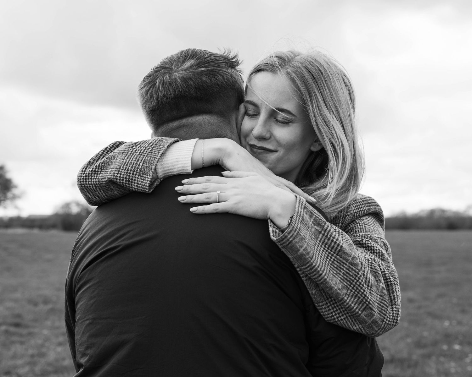 Natural black and white engagement photoshoot of a couple in a field by EvieSJPhotography.