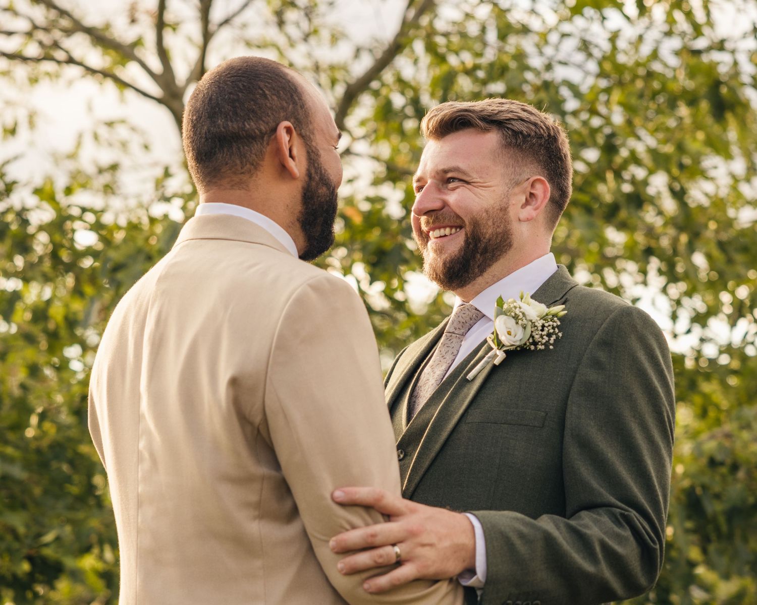 Aaron and Jack share a quiet embrace beneath a tree during golden-hour wedding portraits at Rock Village Hall.