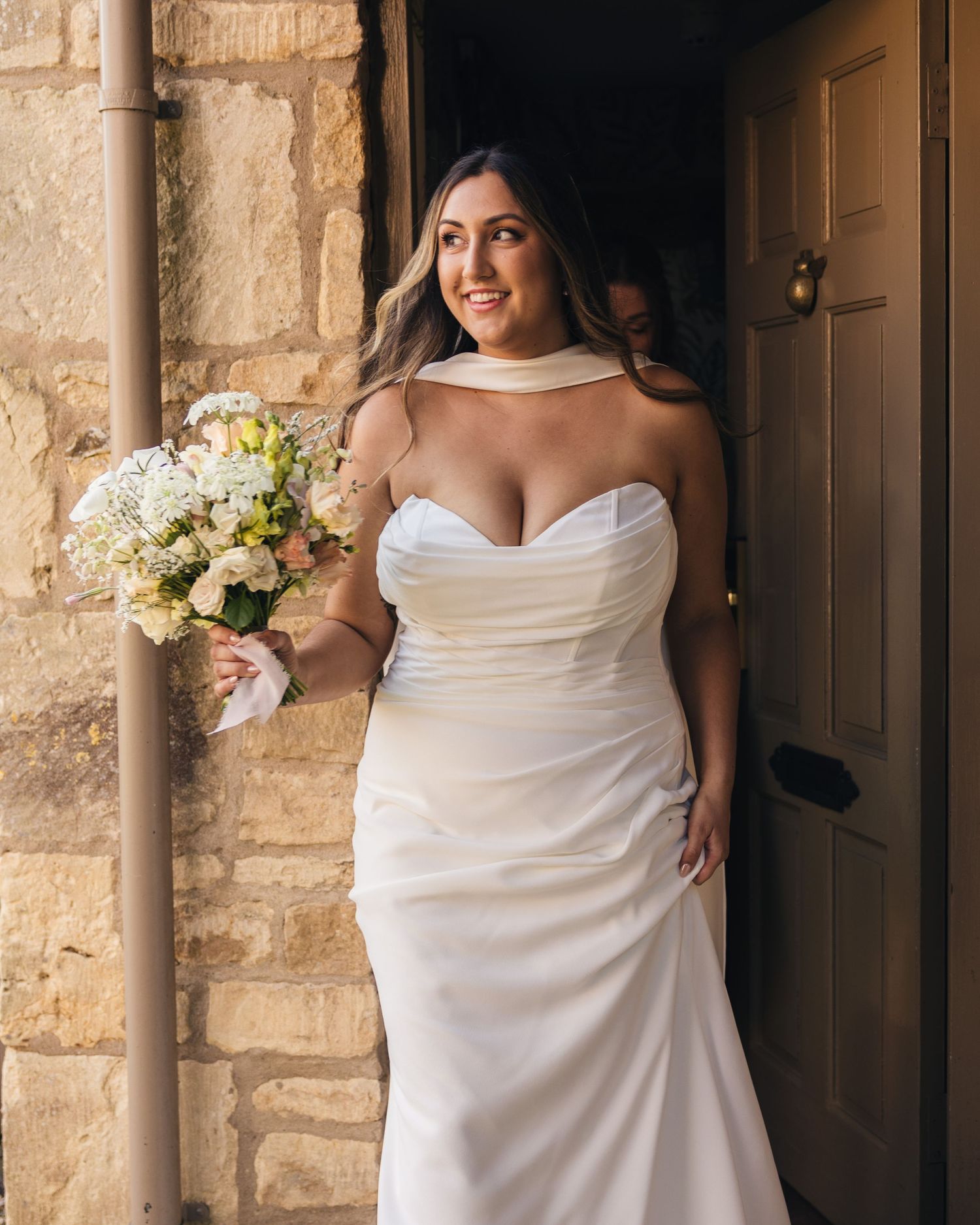 Bride walking out of a cottage to go to her wedding venue.