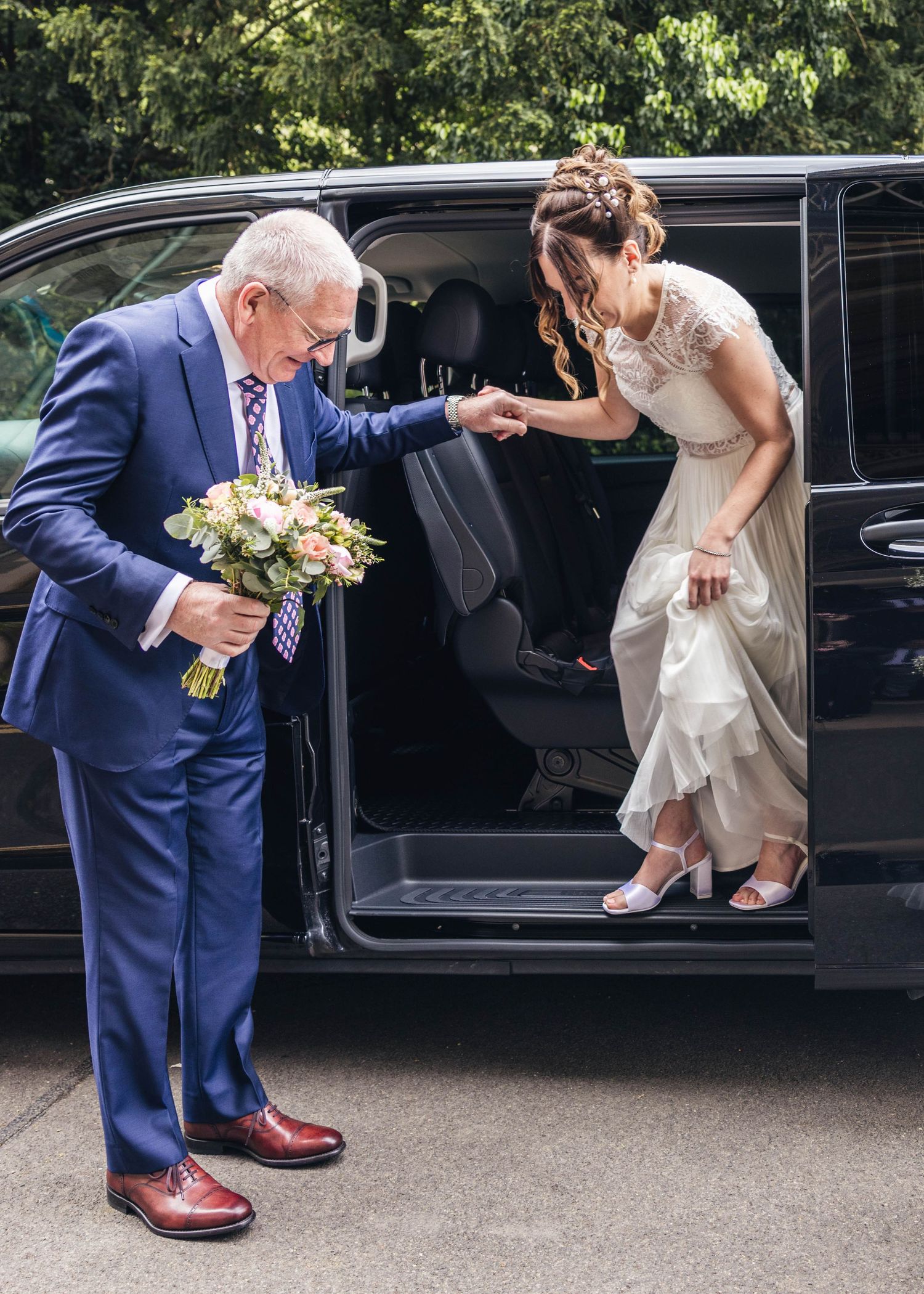 A bride arriving to the registry office, being helped out the car by her father, captured by EvieSJPhotography.