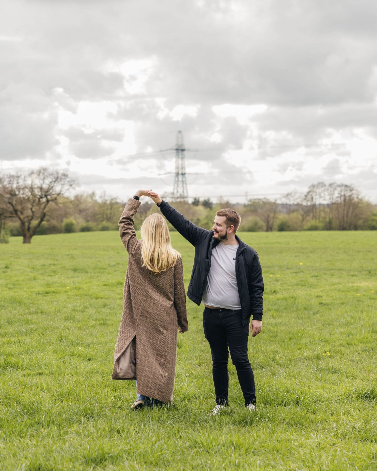 Natural engagement photoshoot of a couple in a field by EvieSJPhotography.
