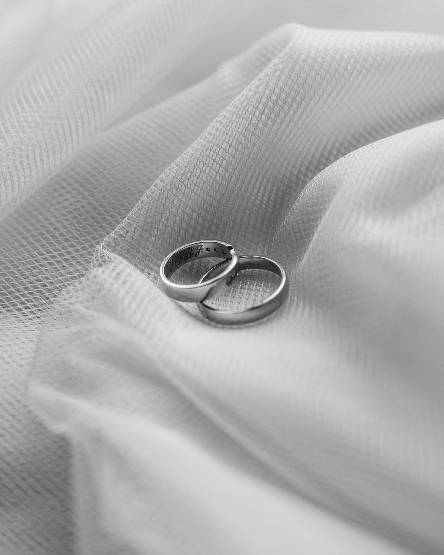 Black and white photo of two wedding rings on top of a white background, captured in a natural, romantic style by EvieSJPhotography.