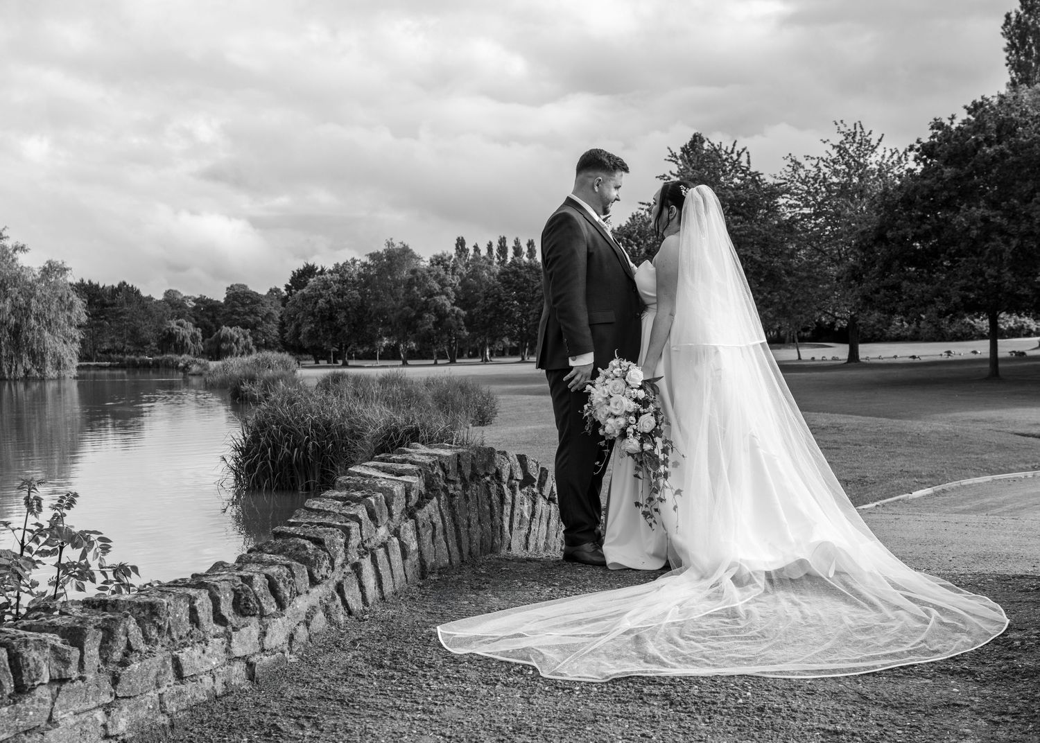 Cortney and Dan standing together on a stone bridge over the lake at Windmill Village Hotel in Coventry.