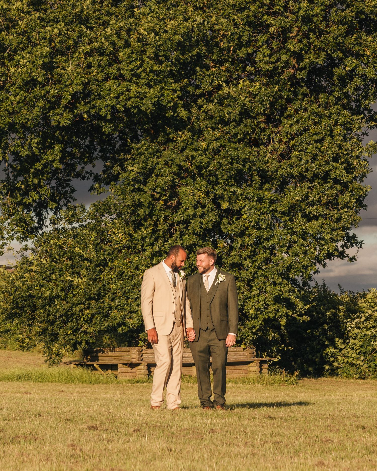 Aaron and Jack share a quiet embrace beneath a tree during golden-hour wedding portraits at Rock Village Hall.