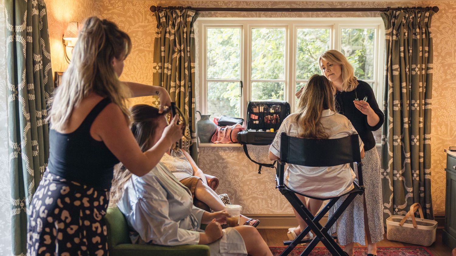 A bride and her bridesmaids having their hair and makeup done for the wedding day, captured by EvieSJPhotography.