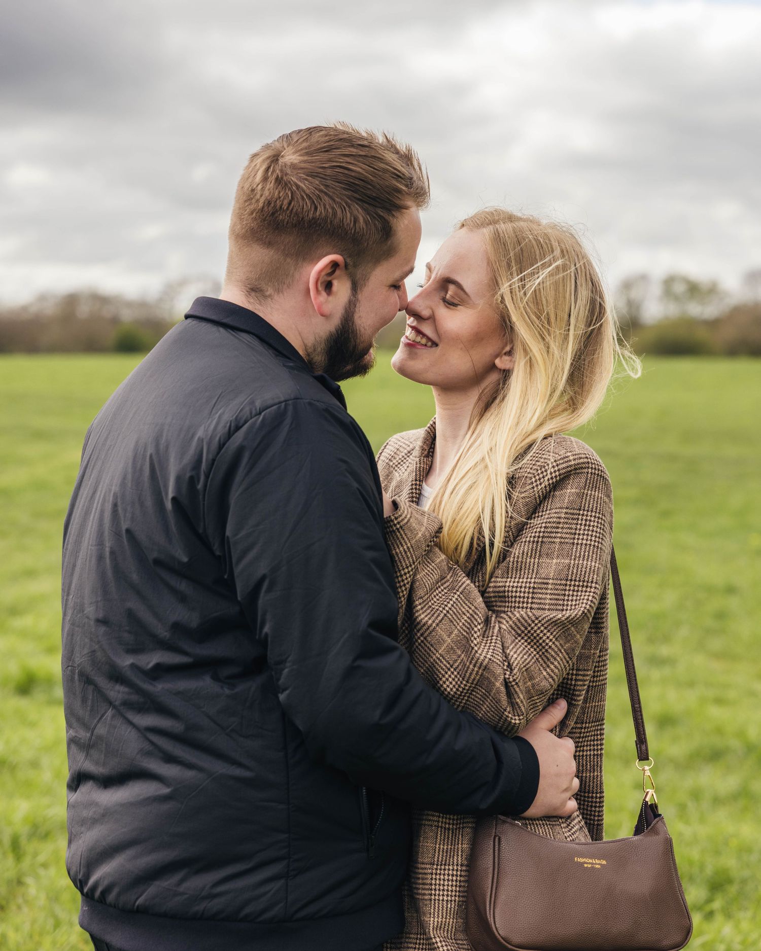 Natural engagement photoshoot of a couple in a field by EvieSJPhotography.