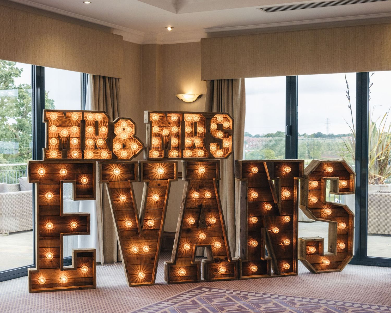 Large illuminated wooden wedding sign displayed inside the Windmill Village Hotel reception room.